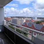 Balkon mit Tisch und Stühlen. Blick auf Stadt und Fernsehturm.