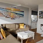 Wohnzimmer mit Sofa, Couchtisch und Fernseher. Wandbild zeigt Strand.