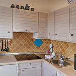 Küche mit weißen Schränken, Mosaikwand und Edelstahlspüle.