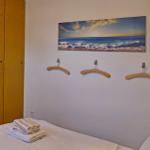 Schlafzimmer mit Bett, Kleiderhaken und Wandbild mit Strandmotiv.