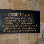 Memorial plaque for Carmen Sylva on the wall, next to a black-and-white photograph.