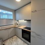 Kitchen with light cabinets, wooden countertop, and window with blinds.