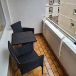 Balcony with table and two chairs, tiled floor and railing.