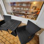 Terrace with table and two chairs, view into interior.