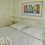 Bedroom with bed, wardrobe, and wall art featuring sailboats.
