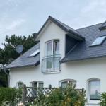 Wohnhaus mit Balkon, Dachfenstern und Satellitenantenne. Umgeben von Grünflächen.
