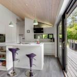 Moderne Küche mit Kücheninsel und Terrasse. Purpurfarbene Barhocker und Holzdecke.