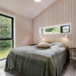 Schlafzimmer mit Holzwand, Bett, Fenster und Tisch.