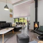 Wohnzimmer mit Sofa, Sessel und Kamin. Durchgang zur Essnische mit Tisch und Stühlen.