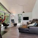 Wohnzimmer mit Ledersofa, großen Fenstern und Holzboden.