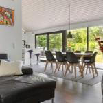 Wohn- und Essbereich mit Sofa, Tisch, Stühlen und Blick auf Garten.