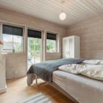 Schlafzimmer mit Holzwand, Bett, Kleiderschrank und Fenstern.