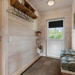 Eingangsbereich mit Holzwand, Garderobe und Sitzbank vor der Tür.