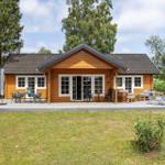Holzhäuschen mit Terrasse, Garten und Liegen. Fenster und Türen sind weiß.