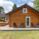 Holzhütte mit Terrasse, Garten und Sitzgelegenheiten. Fenster und Tür sind weiß.