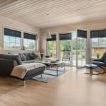 Wohnzimmer mit Sofa, Sessel und Fenstern zur Terrasse.