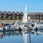 Hafen mit Booten und modernen Häusern im Hintergrund.