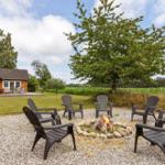 Feuerplatz mit Sitzgelegenheiten im Freien vor einem Holzhaus mit Garten.