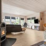 Wohnraum mit Kamin, Sofa, Fernseher und Essbereich. Holzwände und -boden.