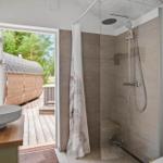 Badezimmer mit Dusche, Waschbecken und Blick auf Holzsauna.