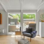 Wohnraum mit Sessel, Tisch und Blick auf Terrasse.