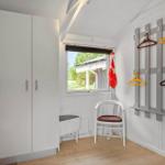 Schlafzimmer mit Kleiderschrank, Stuhl und Garderobe mit Haken.
