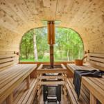 Sauna mit Holzbank, Holzdecke und großem Fenster mit Blick auf Wald.