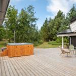 Holzterrasse mit Whirlpool, Sitzgelegenheiten und Blick in den Wald.