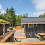 Zwei Häuser mit Holzveranda und Gartenmöbeln. Ein Dach ist begrünt. Hintergrund: Bäume.