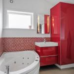 Badezimmer mit Whirlpool, rotem Schrank und Mosaikwand.