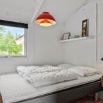 Schlafzimmer mit Bett, Fenster und roter Deckenlampe.