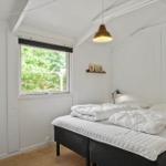 Schlafzimmer mit Doppelbett, Fenster und Deckenleuchte.