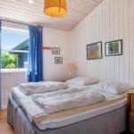 Schlafzimmer mit Bett, blauen Vorhängen und Wandbildern. Holzfußboden und weiße Wände.