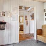 Eingangsbereich mit Stuhl und Schrank. Durchgang zum Badezimmer mit Waschbecken.