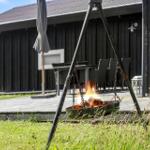 Feuerkorb auf Terrasse vor dunklem Holzhaus mit Grillplatz und Garten.