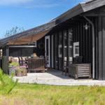 Terrasse mit Tisch, Stühlen und Sonnensegel vor einem Holzhaus.