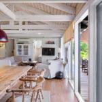 Wohn- und Essbereich mit Holzdecke, Tisch und Stühlen, Fernseher und Blick auf die Terrasse.