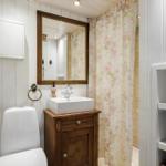 Badezimmer mit Toilette, Waschbecken und Dusche mit floraler Vorhang.