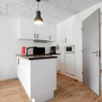 Küche mit Arbeitsplatte, Kühlschrank und Mikrowelle. Tür führt in ein anderes Zimmer.