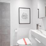 Badezimmer mit Toilette, Waschbecken und Dusche. Wandbild und Spiegel.