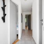 Flur mit Tür zu Schlafzimmer und Fenster. Wandhalter und Bodenfliesen sichtbar.