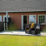 Roter Backsteinbau mit Terrasse, Garten und Sitzgelegenheiten.