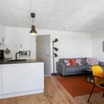 Wohnung mit Küche, Wohnbereich und Essplatz. Ein Sofa, zwei Stühle und eine Kücheninsel.