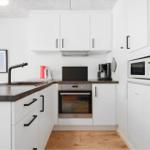 Küche mit weißen Schränken, dunklem Arbeitsplatz und integriertem Ofen.