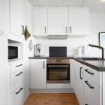 Küche mit weißen Schränken, dunklem Arbeitsplatz und integriertem Backofen.