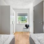 Zwei Betten, ein Schrank, ein Stuhl und ein Fenster mit Blick auf Grün.