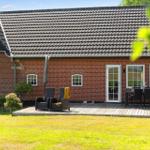 Roter Backsteinbau mit Terrasse, Garten und Sitzgelegenheiten.