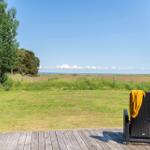 Terrasse mit Sitzgelegenheit und Blick auf Grünland und Horizont.