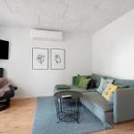 Wohnzimmer mit Sofa, Sessel, Fernseher und Stehlampe.