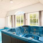 Ein blauer Whirlpool mit mehreren Düsen ist in einem Raum mit großen Fenstern und einer Dachschräge platziert.